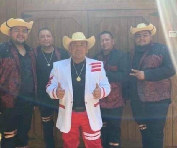 Musicians standing at wooden doors with the cow boy hats