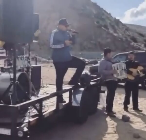 Musician standing on a vehicle and singing along with his troop