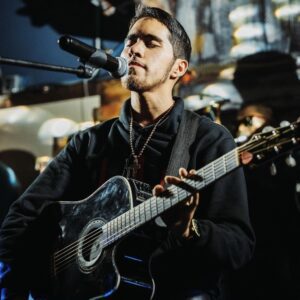 A man singing on a mic and holding a guitar