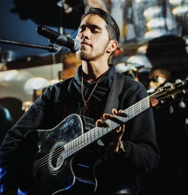 A man singing on a mic and holding a guitar