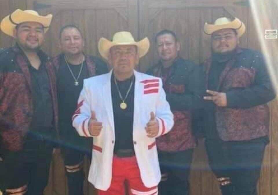 Musicians standing at wooden doors with the cow boy hats